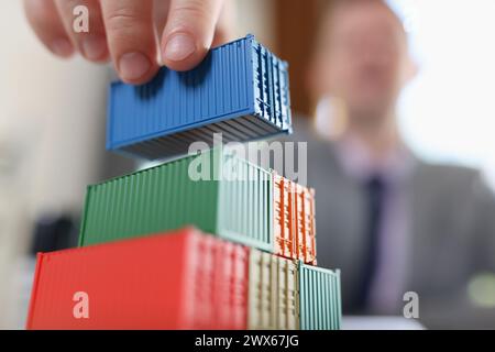 Business man arranging stack of freight containers on his table in office. Stock Photo