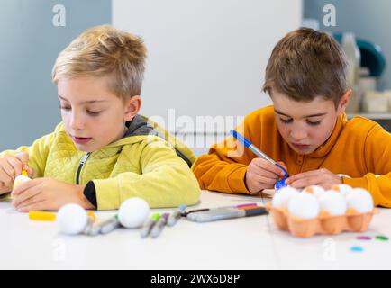 Two children putting colored Easter eggs to decorate Stock Photo