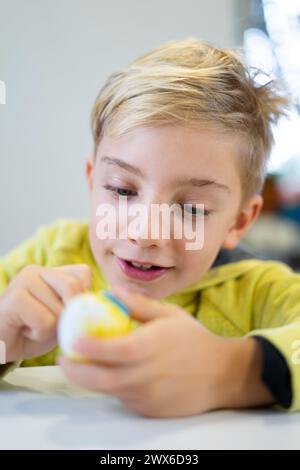 Happy child decorating an Easter egg with marker Stock Photo