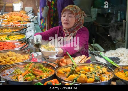London, UK - 12 September, 2023 - A asian muslim female serving curry takeaway at Camden street food market Stock Photo