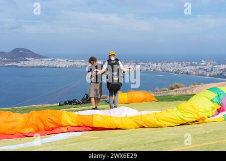 Man learning to paraglide on an island and paragliding teacher checking that all the material is correct Stock Photo