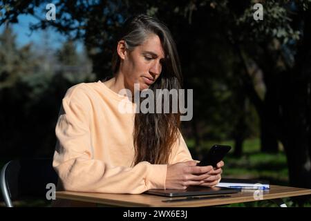 Woman teleworking with her cell phone in the garden of her house Stock Photo
