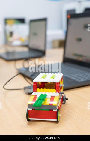 Robot built in a children's robotics workshop with computers in the background Stock Photo
