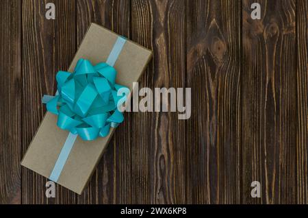 Gift box with a turquoise bow on a wooden table. Top view with copy space for design Stock Photo