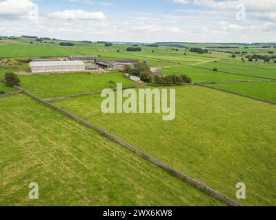 Drone photograph of the Peak District fields and countryside with dry stone walls and a farm in the distance, Derbyshire, UK Stock Photo