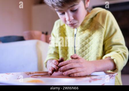 Concentrated boy learning to make ceramic pieces on the potter's wheel Stock Photo