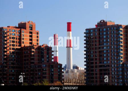 Ravenswood Generating Station power plant smokestacks framed in between apartment buildings on Roosevelt Island, New York City Stock Photo