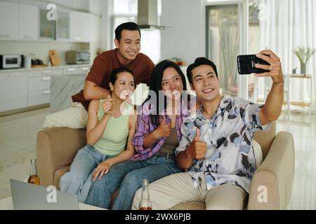 Happy Vietnamese man taking selfie with friends at home Stock Photo