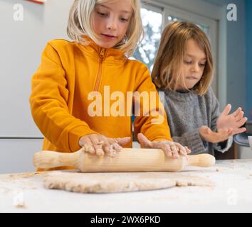 Two brothers kneading dough to make pizza at home Stock Photo