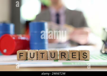Word futures collected from wooden cubes with oil barrels and blurred business person in background. Stock Photo