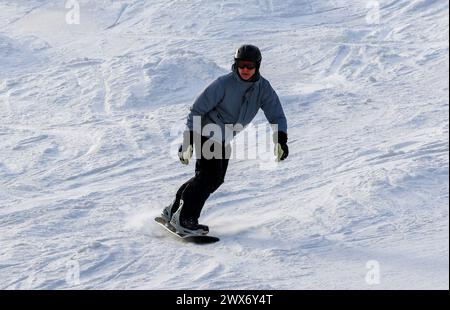 Mount Snow, Vermont, USA - 31 January 2023: one male snowboarder making his way down the mountain on New Years Eve 2023. Stock Photo