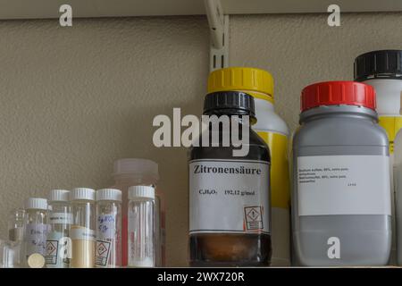 Shelf filled with various chemical bottles with labels. Stock Photo