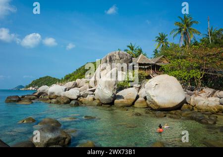 Tropical island paradise, Tourist family swim in turquoise clear water, Hurt behind big boulders. Romantic hidden vacation place. Koh Tao island popul Stock Photo