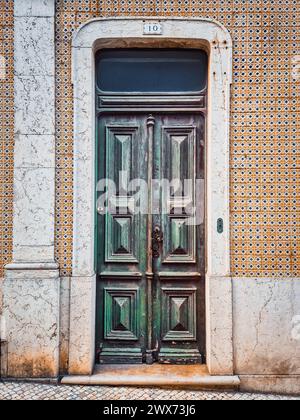 Facade of old house with weathered green wooden door and beautiful tile work or azulejos on the walls. Vintage traditional architecture Stock Photo
