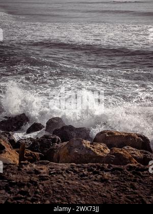 A wave splash hitting against a rocky coast of the Atlantic Ocean in Gala, Portugal Stock Photo