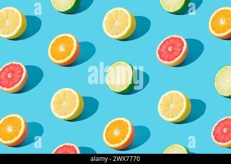 Colorful sunlight fruit pattern made of red grapefruit, orange, lime and lemon slices on light blue background. Minimal summer concept. Creative food Stock Photo
