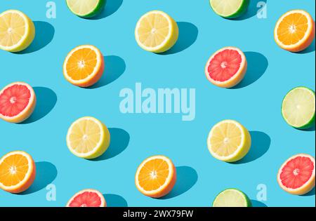 Colorful sunlight fruit pattern made of red grapefruit, orange, lime and lemon slices on light blue background with copy space. Minimal summer concept Stock Photo