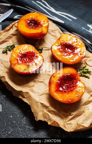 Baked peaches with honey and cinnamon on black stone background. summer dessert Stock Photo