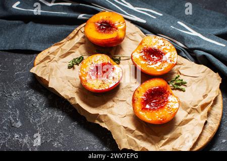 Baked peaches with honey and cinnamon on black stone background. summer dessert Stock Photo