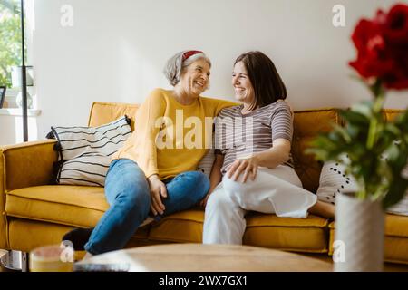 Happy senior woman talking with daughter-in-law while sitting on sofa at home Stock Photo