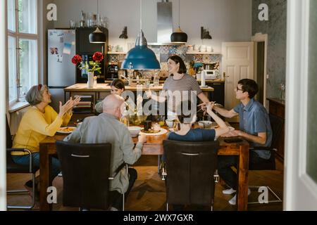 Happy multi-generation family enjoying while having lunch together at dining table in home Stock Photo