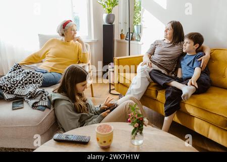 Mother and son talking with senior woman sitting on chair at home Stock Photo