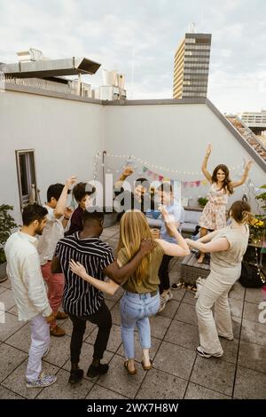 Group of friends dancing on rooftop deck at party Stock Photo