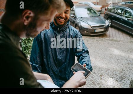 High angle view of smiling delivery person taking electronic signature from man at doorstep Stock Photo