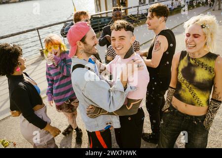 High angle portrait of smiling non-binary person standing with friends on promenade in city Stock Photo