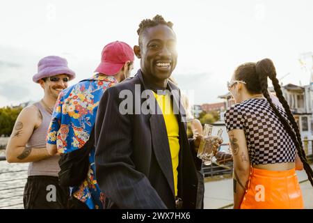 Portrait of happy non-binary person with friends having fun in background Stock Photo