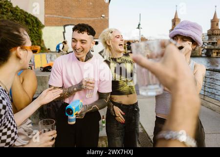 Happy non-binary friends having fun while partying on promenade in city Stock Photo