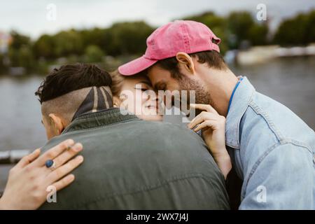 Smiling non-binary person embracing friends Stock Photo