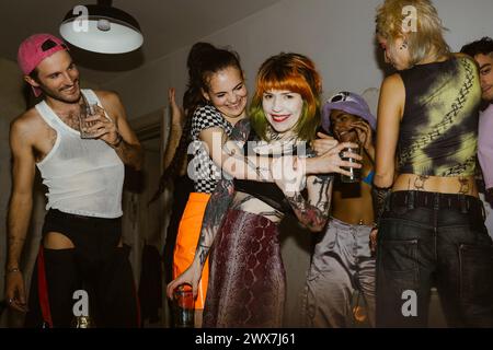 Smiling non-binary person embracing female friend in party at nightclub Stock Photo