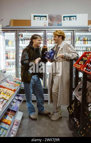 Happy gay couple talking with each other while having snacks at supermarket Stock Photo