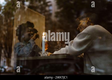 Low angle view of happy multiracial couple having fun during date at restaurant Stock Photo