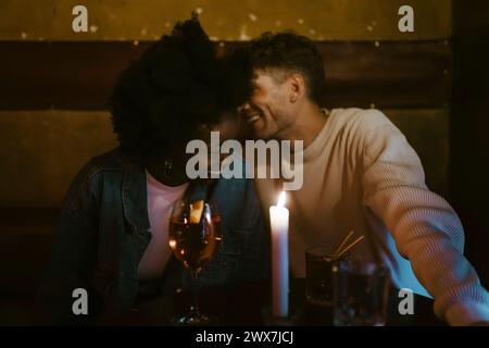 Happy multiracial couple having fun during candlelight date at bar Stock Photo