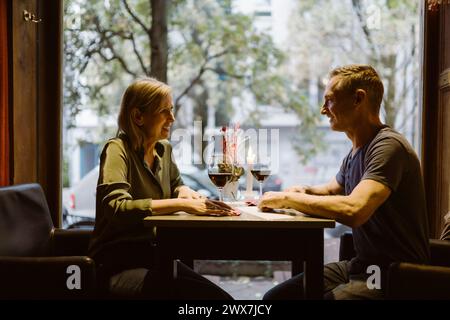 Smiling mature couple looking at each other while having wine at bar Stock Photo
