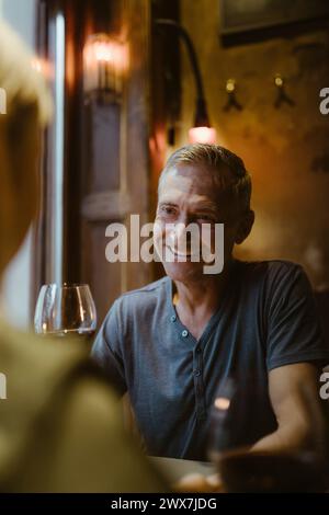 Smiling man talking to woman while sitting during date at restaurant Stock Photo