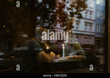 Happy mature couple having fun during date at restaurant seen through glass Stock Photo
