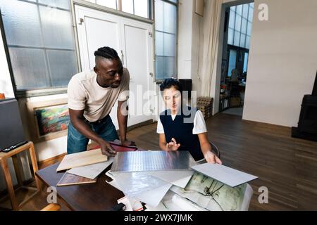 Male and female architects discussing over building material sample at studio Stock Photo
