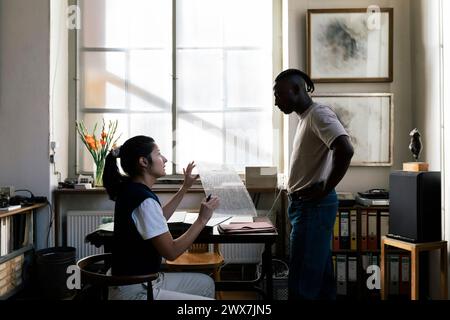 Female entrepreneur discussing over building material sample with male colleague in workshop Stock Photo