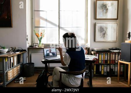 Businesswoman showing document on video call to male colleague at workplace Stock Photo