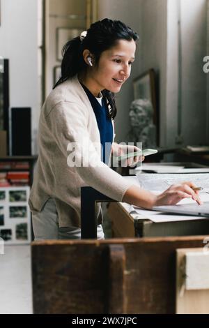 Smiling businesswoman using laptop while working at home office Stock Photo