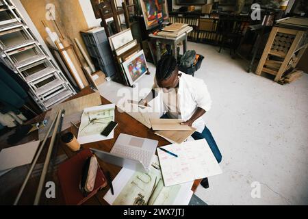 Directly above shot of male architect examining wooden swatch while sitting in workshop Stock Photo