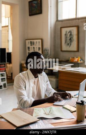 Male entrepreneur working on laptop while sitting at workplace Stock Photo