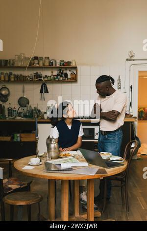 Businesswoman discussing with male colleague in kitchen of home office Stock Photo