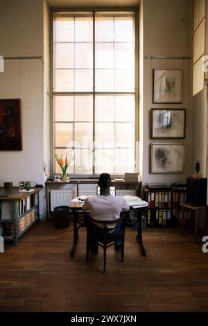 Rear view of businessman working on laptop while sitting at workplace Stock Photo