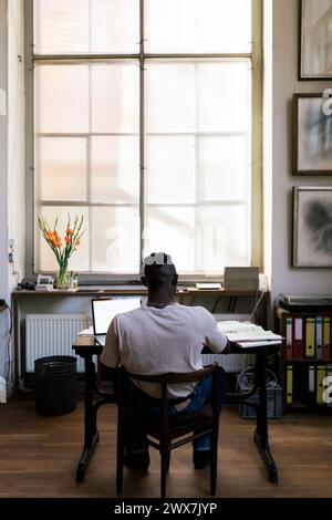 Rear view of male designer using laptop while working in studio Stock Photo
