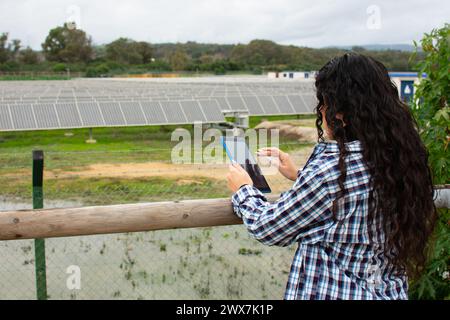 an engineer checking the performance of the solar panels with her tablet. Stock Photo