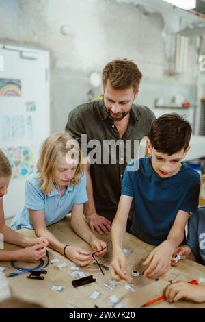 Male teacher assisting students during technology class Stock Photo